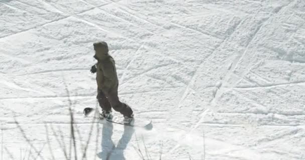 Snowboardista jde po sněhové dráze a skočí na konec. - Záběry, video