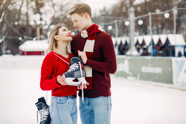 Cute couple in a red sweaters having fun in a ice arena - Photo, image