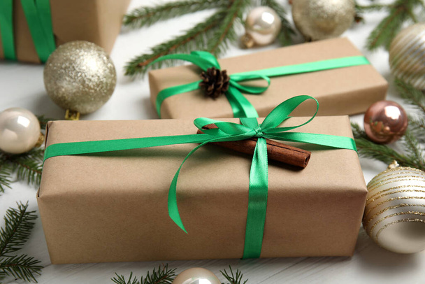 Gift box with green ribbon and Christmas decor on white wooden table, closeup - 写真・画像