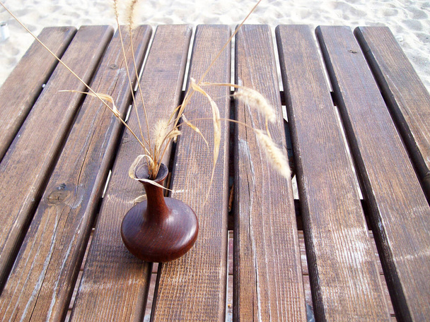 ikebana, droge bloemen in een kleine vaas op een houten ondergrond. - Foto, afbeelding