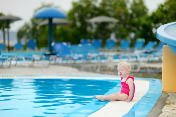Adorable toddler girl sitting by a swimming pool - Foto, Imagen