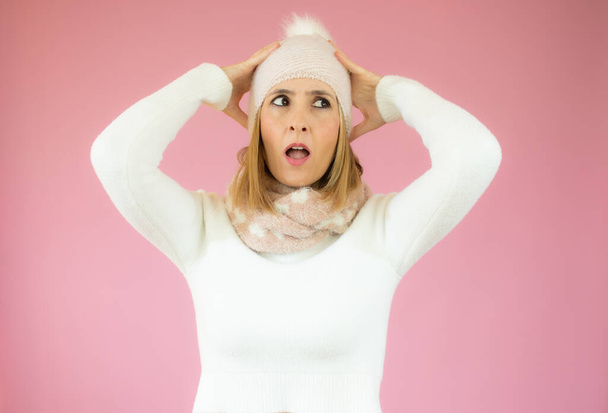 Portrait of a young woman wearing winter clothes surprised isolated over pink background - Photo, Image