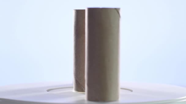 Vídeo 4k de três rolos de papelão do papel higiênico usado que gira em uma plataforma giratória. Foco seletivo - Filmagem, Vídeo