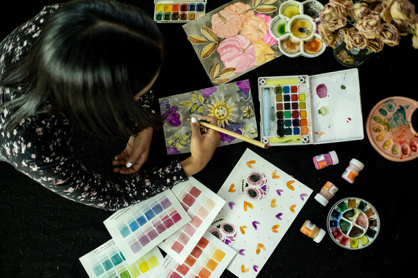 Egy nő fekszik a takarón, akvarelles festménnyel, a hobbiját otthon csinálja, fejlövés. - Fotó, kép