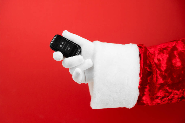 Santa Claus hand holds car keys. Merry Christmas and New Year concept. New car smart key. Buyer, property, buy, rent, sale, truck, cars concept. - Φωτογραφία, εικόνα