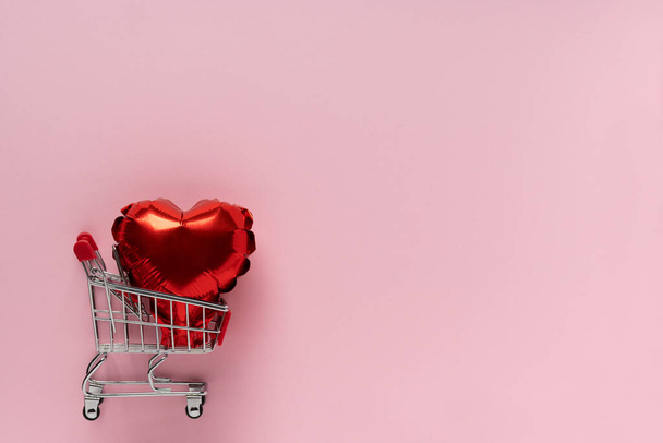 Valentines day, Top view red heart baloon on mini shopping cart on pink background, copy space, love concept - Photo, Image