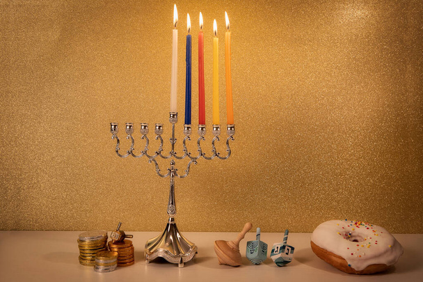 Dia 4 de feriado religioso judaico Hanukkah com menorah lustre tradicional, girando brinquedos de topo (dreidels) e um donut e moedas de chocolate em mesa de madeira branca e fundo dourado brilhante - Foto, Imagem