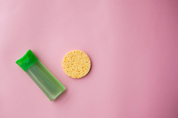 Green cleansing gel for the face and sponge for cleansing the skin on a pink background. Cosmetic products. Skin care. selective focus. - Foto, imagen
