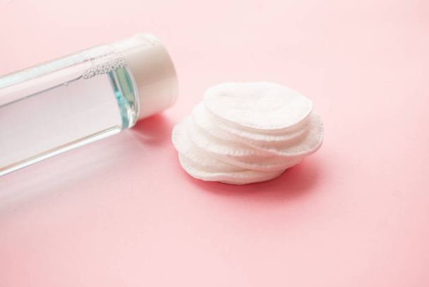 cotton pads, bottle with tonic or micellar cleansing water with fresh herbs and flowers on pink background, top view. Beauty, skin, hair or body care concept.selective focus. - Foto, Bild