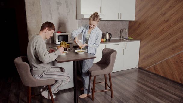 Happy young family, wife and husband, having Breakfast at the table in the morning in the kitchen without children. Cornflakes with milk and bananas. - Foto, Bild