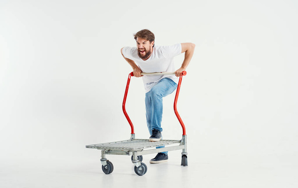 a man in a cargo trolley on a light background superhero transporting heavy objects - Foto, Imagem