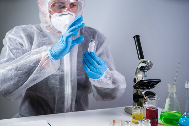 Development and search for drug for coronavirus. Chemist examining ampoule of powdered antibiotic for injection. Treating bacterial infection with medications. Covid 19 health and treatment concept. - Photo, Image