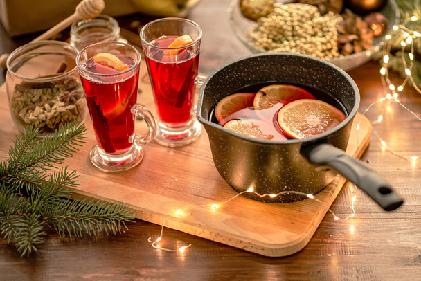 Vino rimuginato rosso in tavola, decorazioni natalizie sullo sfondo. Processo di cottura. - Foto, immagini