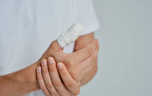 man in white t-shirt bandaged thumb health problems medicine - Photo, Image