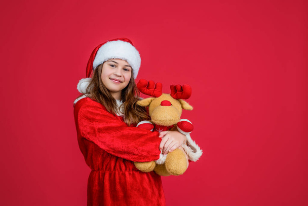 szczęśliwy Boże Narodzenie dziewczyna nosić czerwony Santa Claus kapelusz i kostium grać z reniferów zabawki, sklep z zabawkami - Zdjęcie, obraz
