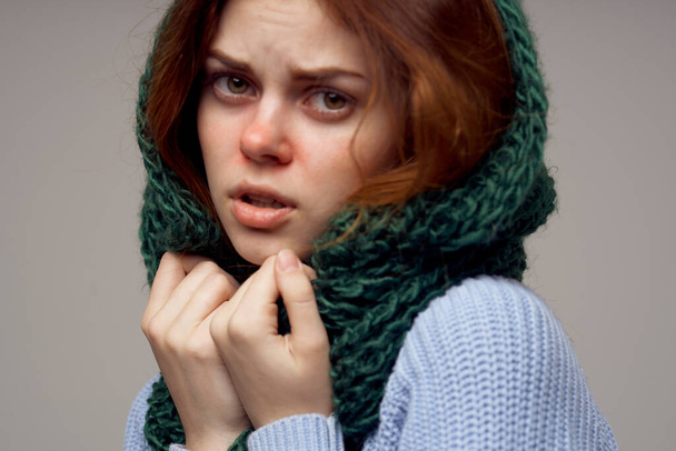 women in a knitted headdress and in a blue sweater on a gray background health problems runny nose - Foto, imagen