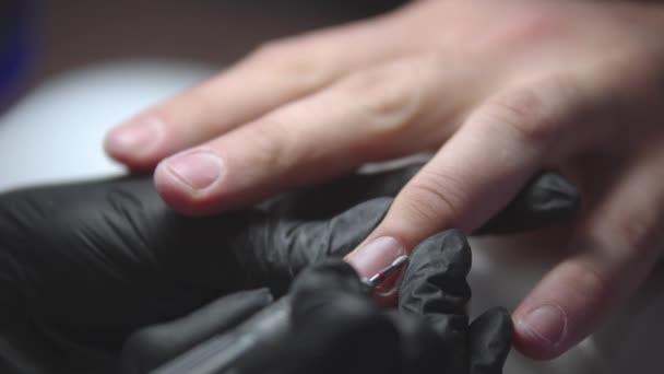 Μανικιουρίστα κάνει manicure mans χρησιμοποιώντας μια μικρή συσκευή γεώτρησης - τον καθαρισμό της ζώνης των πετσετών - Πλάνα, βίντεο