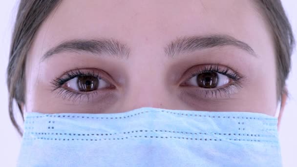 Extrémní zblízka. Žena v masce obličeje pro prevenci a ochranu virové infekce. Žena otvírá a zavírá oči. Coronavirus (2019-nCoV), COVID-19, pandemie, koncepce izolace. 4K, zpomalený pohyb - Záběry, video