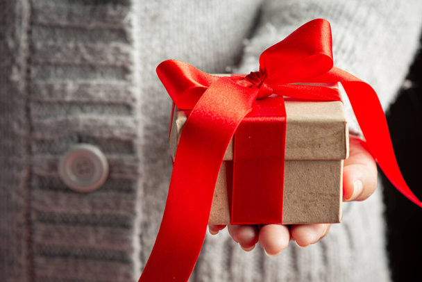woman's hand holding a gift box with red ribbon - Fotografie, Obrázek