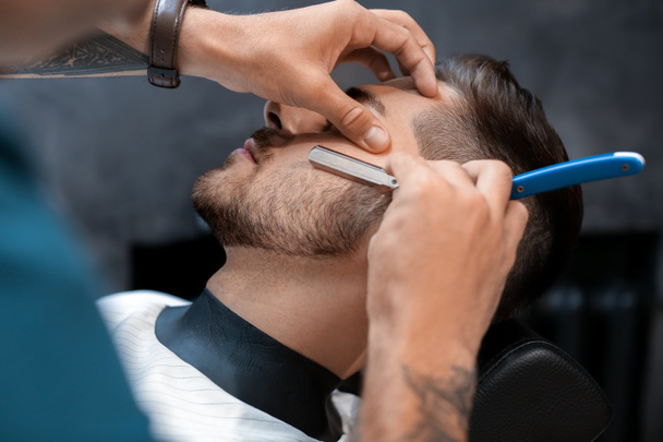 Hairdresser shaving client in barbershop - Photo, Image