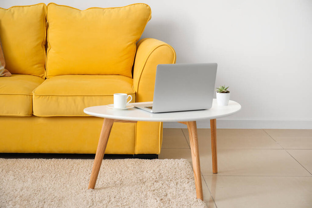 Stylish sofa and laptop near light wall in room - Foto, Bild