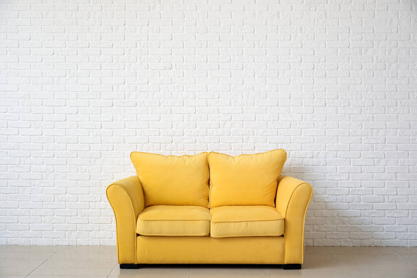 Stilvolles Sofa in der Nähe der Ziegelwand im Zimmer - Foto, Bild