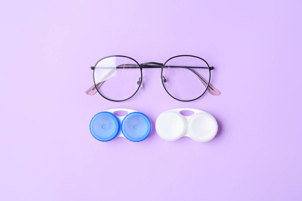 Pojemniki z soczewkami kontaktowymi i okularami na kolorowym tle - Zdjęcie, obraz