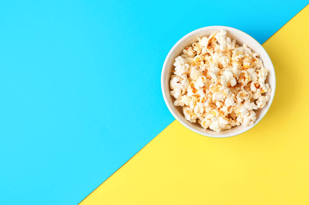 Schaal van lekkere popcorn op kleur achtergrond - Foto, afbeelding