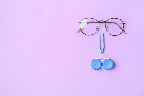 Контейнер с контактными линзами, пинцетом и очками на цветном фоне - Фото, изображение