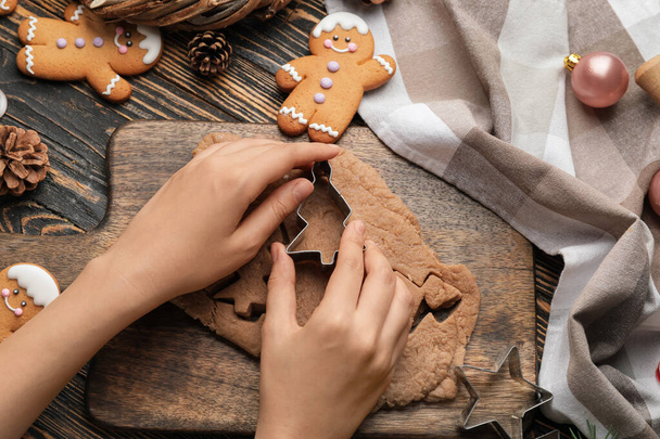 Woman preparing tasty Christmas cookies at wooden table - Foto, afbeelding