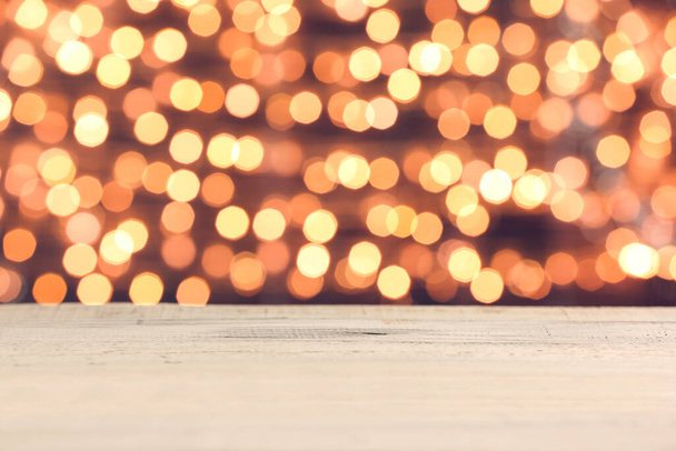 Tavolo in legno vuoto contro le luci di Natale sfocate - Foto, immagini