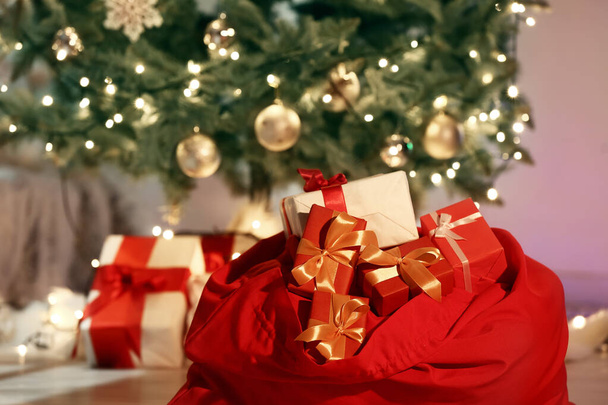 Bolso de Santa con regalos en la habitación decorada para Navidad por la noche - Foto, imagen