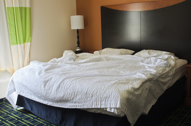 onordelijk bed in hotel slaapkamer - Foto, afbeelding