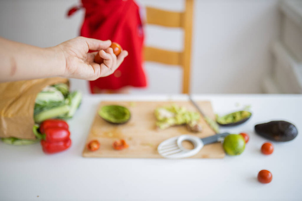 La mano femenina que da los tomates pequeños a la chiquilla a la mesa - Foto, imagen