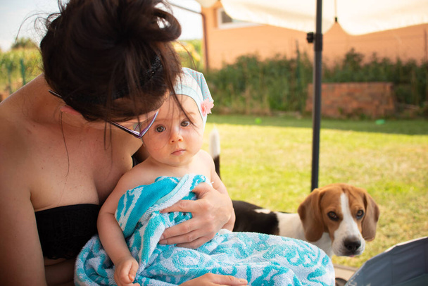 Mãe segurando bebê menina no colo, coberto com toalha após a natação. - Foto, Imagem