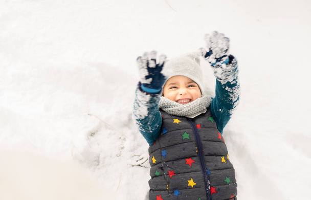 kleine jongen met hoed en handschoenen spelen in de sneeuw - Foto, afbeelding