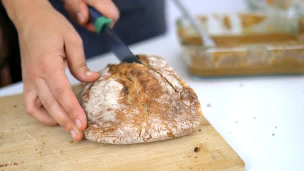 Vrouwelijke handen snijden brood op een snijplank - Video