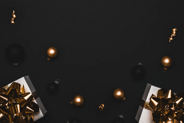 Gelukkig 2021. Witte geschenkdoos met gouden lint, Nieuwjaarsballen en fonkelende lichtslinger in kerstcompositie op zwarte achtergrond voor wenskaart. Kerstmis, winter, nieuwjaarsconcept - Foto, afbeelding