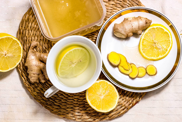 Warming drink with lemon and honey. Saucer with ginger and lemon. The concept of prevention and treatment of flu and colds. The view from the top. - Photo, Image
