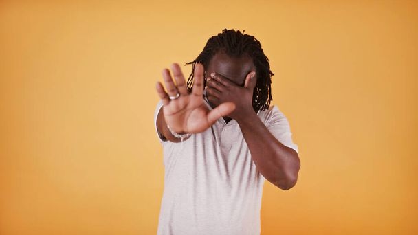Halt. Junger afrikanisch-amerikanischer schwarzer Mann hält Hand über die Augen und zeigt Halt mit der anderen Hand - Foto, Bild