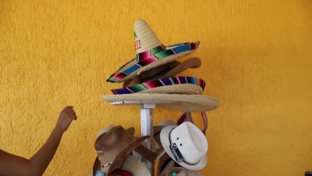 伝統的なメキシコの帽子のスタックからソムブレロを選ぶ女性のビデオ - 映像、動画