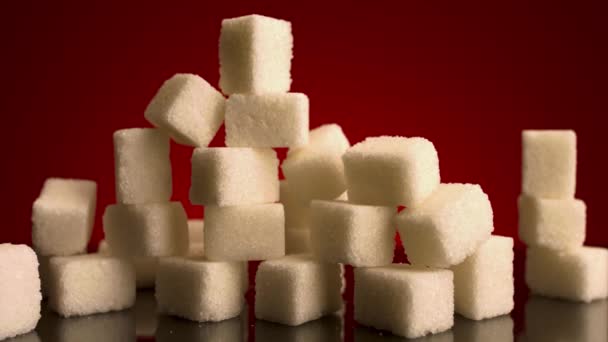 Close up of many sugar cubes standing on the top of each other isolated on red background. Stock footage. Concept of candy, sweets and food.  - Footage, Video