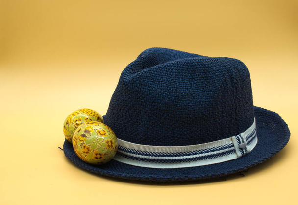 Elegant blue straw hat with an egg on it isolated on neutral orange background - Φωτογραφία, εικόνα