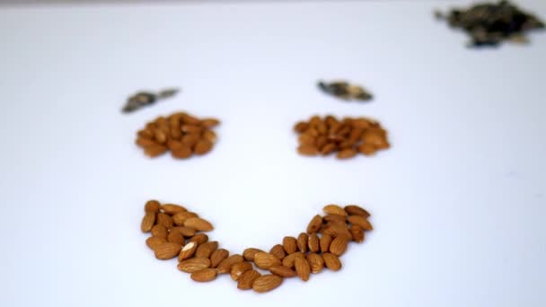 Pequenas pilhas de amêndoas e sementes de girassol em uma forma de rosto sorridente - Filmagem, Vídeo