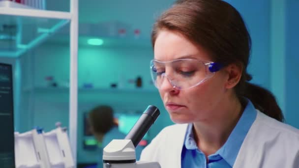 zbliżenie chemik kobieta lekarz patrząc przez mikroskop - Materiał filmowy, wideo
