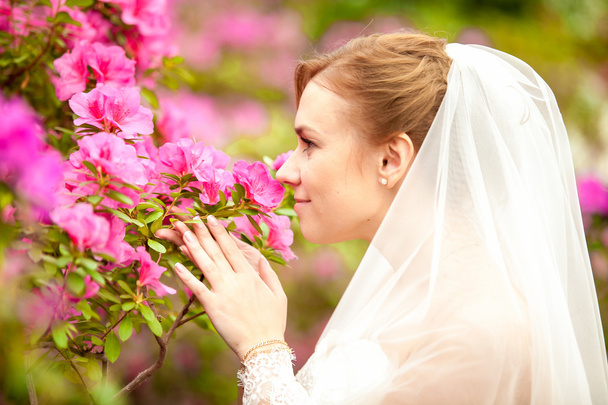 Portrait of beautiful bride smelling pink flowers - Zdjęcie, obraz