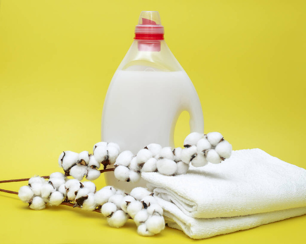 Laundry Detergent in bottle with Liquid and towels on yellow background with cotton ball. Washing concept - Photo, Image