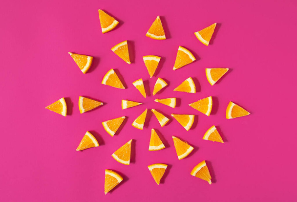 Геометрична мандала з апельсинових фруктових скибочок на рожевому
 - Фото, зображення