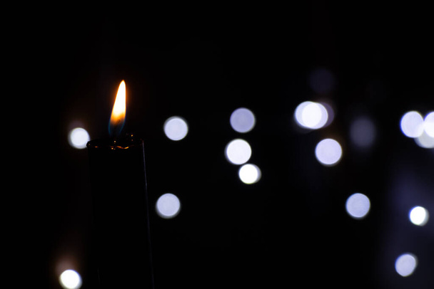 candle flame in the dark on the background of blurry garlands bokeh, religion - Foto, afbeelding