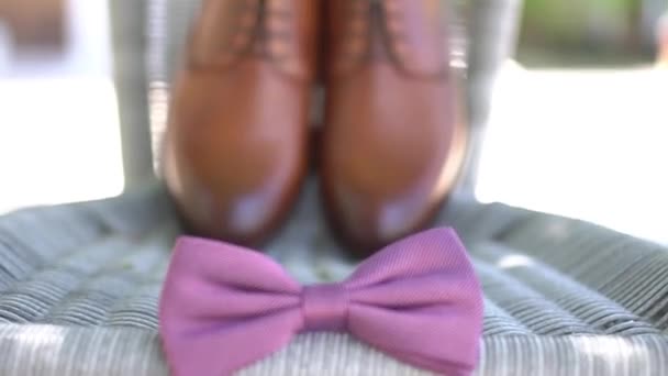 the grooms bow tie lies near leather shoes standing on a wicker chair while getting ready - Footage, Video